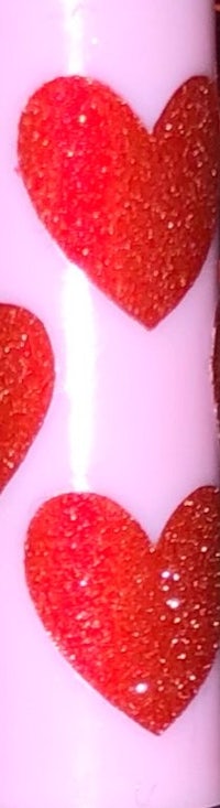 a close up of a candle with red hearts on it