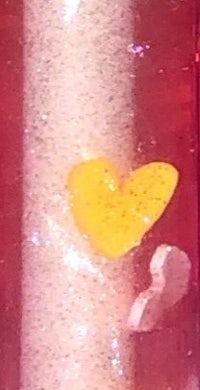 a close up of a bottle with a yellow heart in it